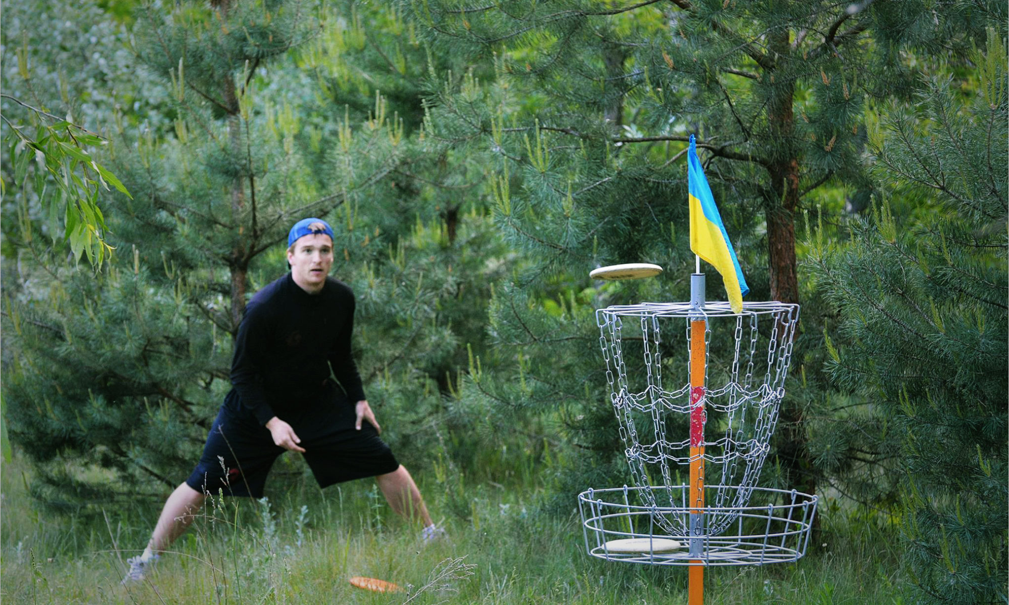 Гравець кидає диск в кошик для диск-гольфу. Фото: discgolf.in.ua